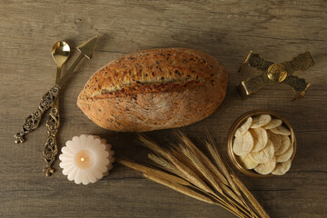 Bread, spikelets and candle on wooden background, top view