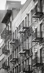 Black and white photo of buildings with fire escapes, New York City, USA.