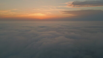 Orange cloudy sky horizon aerial view. Golden skyline over white fluffy clouds