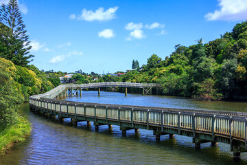 Wooden pathway over calm waters of Orakei Basin. Gorgeous nature walk in Auckland, New Zealand