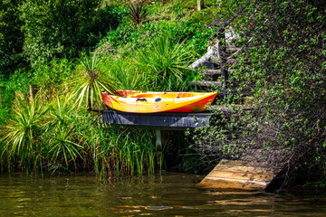 Bright yellow kayak drying on a private jetty hidden in the lush green at the bottom of a steep hill