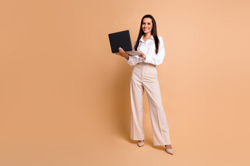 Full body photo of lovely elegant lady use wireless laptop networking empty space isolated on beige color background