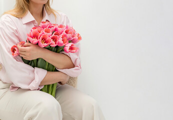 Girl in pink shirt and light colored pants holding a large bouquet of pink tulips.
