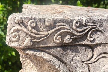 Ancient stone carving, scrolls and floral patterns, sunlight, nature background. Side ancient city, Manavgat, Turkiye (Turkey)