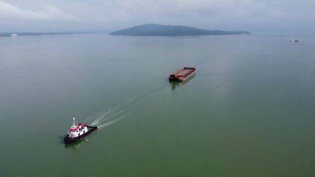 Aerial view of a tugboat towing an empty barge in the Kalimantan sea