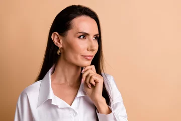 Gardinen Photo of pretty intelligent manager lady hand touch chin look interested empty space isolated on beige color background © deagreez