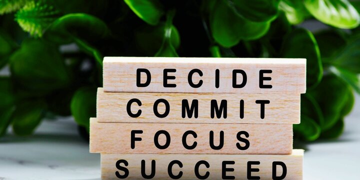 DECIDE,COMMIT, FOCUS, SUCCED word made with building blocks. Wooden Blocks. The text is written in black letters