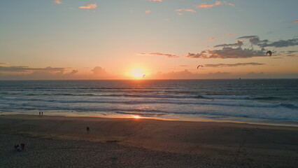 Sea surf washing sunrise shore aerial view. Power kites flying people walking