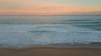 Fototapeta na wymiar Orange sunset ocean horizon over foamy waves aerial view. Surf rolling coast
