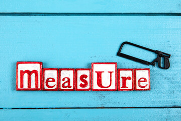 MEASURE. Miniature saw on a blue wooden background. construction and carpentry concept