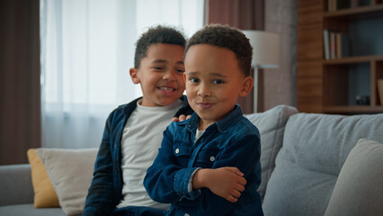 Two funny African American children siblings after quarrel at home funny boy kid pretend offended ignoring joking pretending frustrated sad ignore brother sorry apologize make peace calming friend - obrazy, fototapety, plakaty