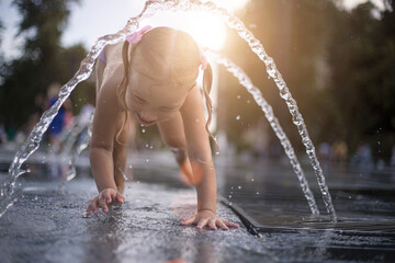 A little girl bathes under the streams of a fountain
