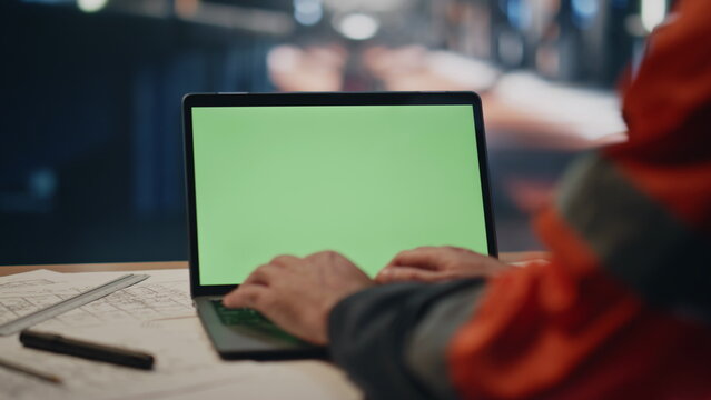 Factory worker typing green screen laptop on plant workshop close up. Engineer