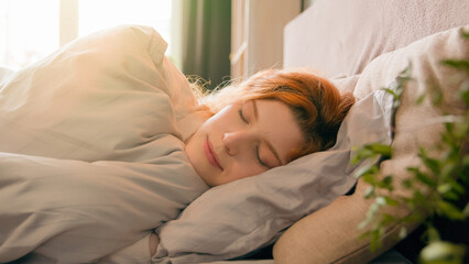 Sleepy beautiful woman waking up lying in comfortable white bed smiling toothy happy smile carefree...