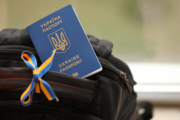 Ukrainian biometrical passport on black touristic backpack with ukrainian ribbon close up