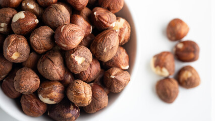 Close up of hazelnuts in a bowl on white background.