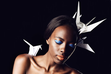 Black woman, makeup and fine art with beauty, cosmetics or origami birds on a dark studio...