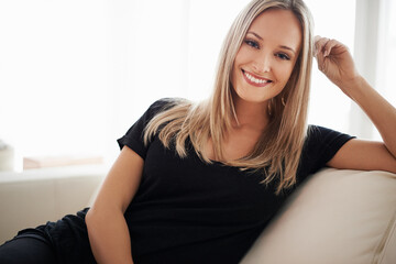 Happy, portrait and woman on a sofa relax with confidence, positive attitude or leisure in her home. Face, smile and female person in a living room with vacation, free time or resting holiday