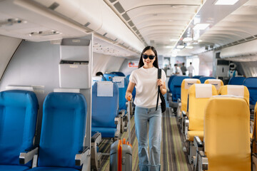 Asian woman sitting in a seat in airplane and looking out the window going on a trip vacation...