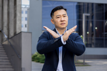 Confident businessman in a blue suit making a stop gesture outdoors