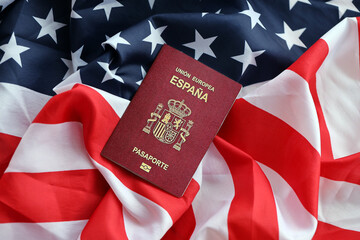 Red Spanish passport of European Union on United States national flag background close up. Tourism...