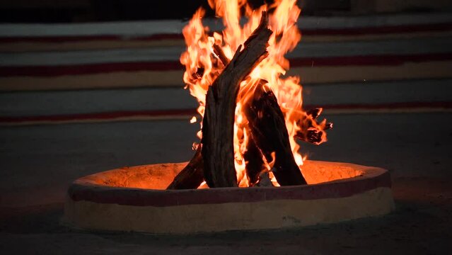 small bonfire made of logs in a brick firepit showing camping in the desert in rajasthan or the hills of shimla, manali and more with cold chilly evenings