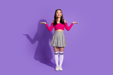 Full size photo of positive cheerful girl dressed checkered skirt palms presenting products empty space isolated on purple background