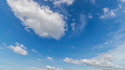 Obraz premium Panoramic view of clear blue sky and clouds, Blue sky background with tiny clouds. White fluffy clouds in the blue sky. Captivating stock photo featuring the mesmerizing beauty of the sky and clouds.