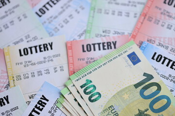 Many lottery tickets and euro bills on blank bills with numbers for playing lottery close up