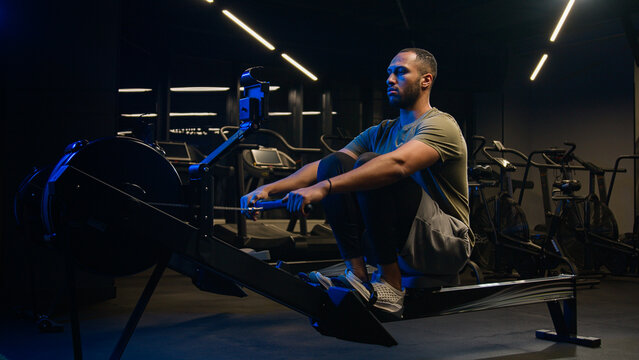 Sport hard weight exercise sporting bodybuilding workout gym pulling rowing machine sitting lift low row motivation healthy African American man sporty male guy athlete sportsman bodybuilder trainer