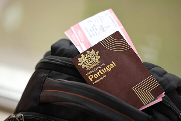 Red Portugal passport of European Union with airline tickets on touristic backpack close up. Tourism and travel concept