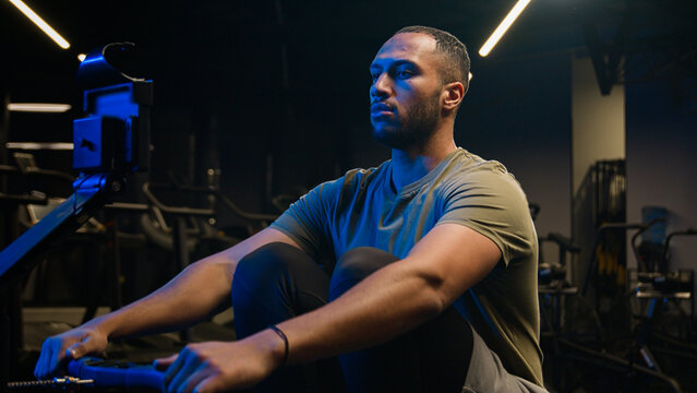 Sport workout in gym exercise with rowing machine simulator sitting dead lift low row in sportive club effort goals motivation health African American man sporty male guy athlete sportsman bodybuilder