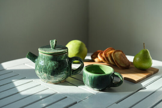 Delicious breakfast, snack pancakes, green tea, fresh pear, green teapot, tea on a gray background, morning sun . High quality photo