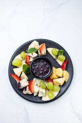 Cheese platter with grapes, blueberry jam and fresh strawberries
