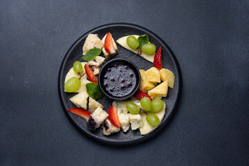 Cheese platter with grapes, blueberry jam and fresh strawberries
