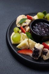 Cheese platter with grapes, blueberry jam and fresh strawberries