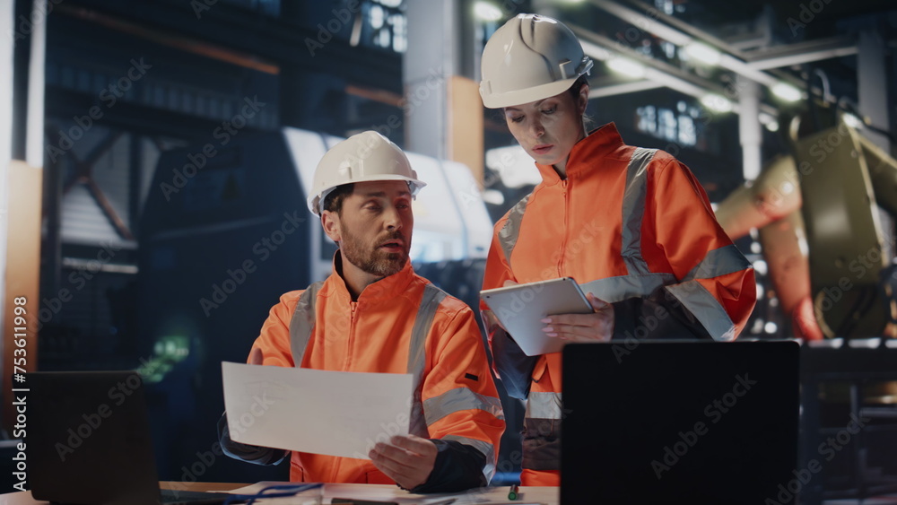 Wall mural two busy engineers working in industrial workshop. woman technician looking