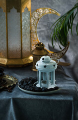 Dates in a crescent moon shape plate with lantern lamp, iftar Ramadan food concept image