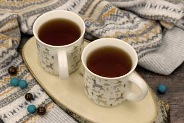 Cozy atmosphere with tea and a warm sweater. Poster for interior. Two mugs of hot tea and warm clothes will keep you warm during the cold season.