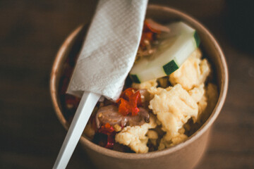 cup bowl rice with stuffing Fried Chicken Slices, raw chili sauce, scrambled eggs, Carrots and Yogurt Mayonnaise Sauce in a Cardboard Glass Container.