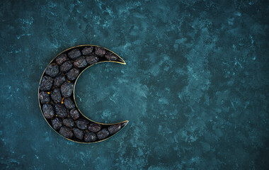 Dates in a crescent moon shape plate isolated on dark grey texture background, Ramadan iftar food...