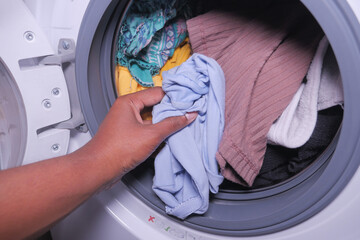  man putting shirt into washing machine.