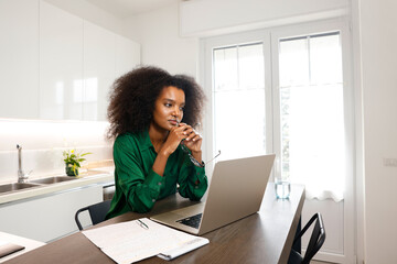 An African American woman holding her hands thinking deep and hard at home, working