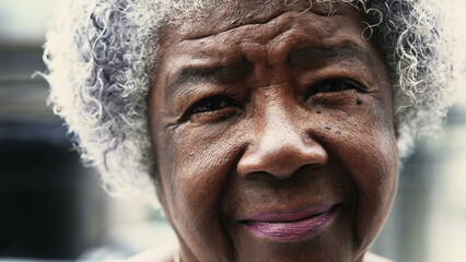 African American elderly lady in 80s with solemn expression expressing old age and wisdom. Gray hair wrinkled portrait of a black senior woman staring at camera outside in drizzle