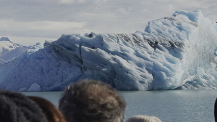 Tourists Gaze at Majestic Iceberg from a Navigating Boat