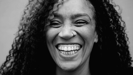 Monochromatic close-up face of a joyful 40s woman from South America smiling and laughing. One...