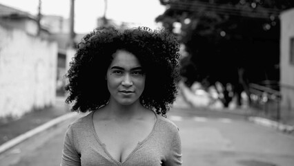 One confident young black woman walking towards camera outside in urban street environment in...