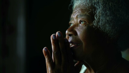 Faithful and Spiritual Senior African American woman with gray hair opening eyes feeling GRATEFUL...