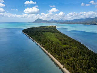 Aerial view of a lush green peninsula with a sandy beach dividing turquoise waters under a blue sky.