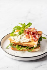 Toasts sandwich with rugula, bacon and cream cheese on white plate marble background. Isolated, text space